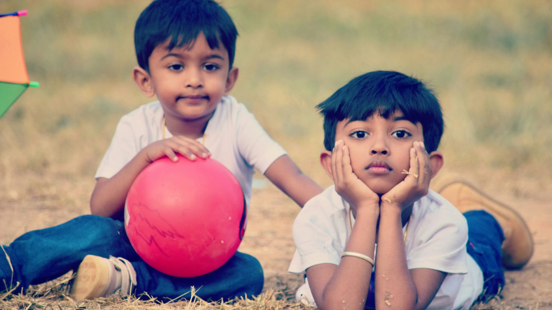 twin children wearing white crew-neck t-shirt on brown field