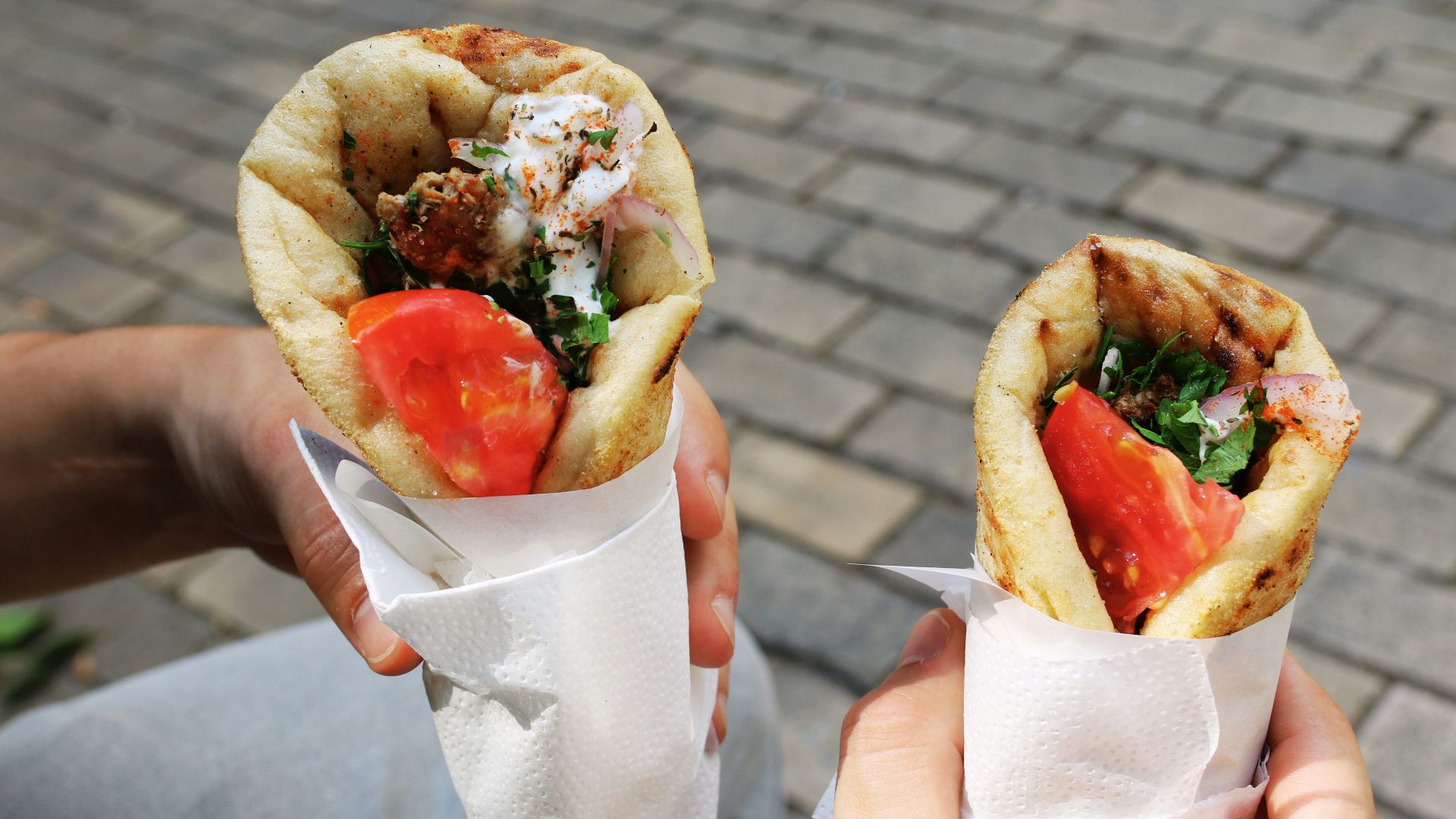 A person holding two sandwiches in their hands