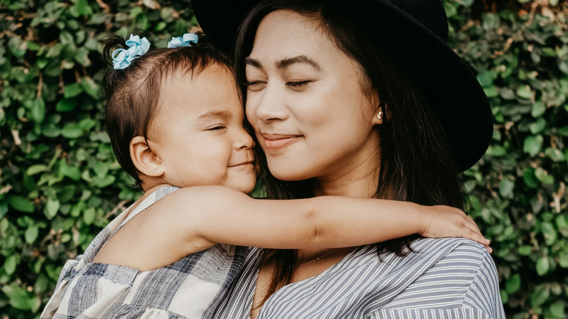 woman carrying child beside hedges