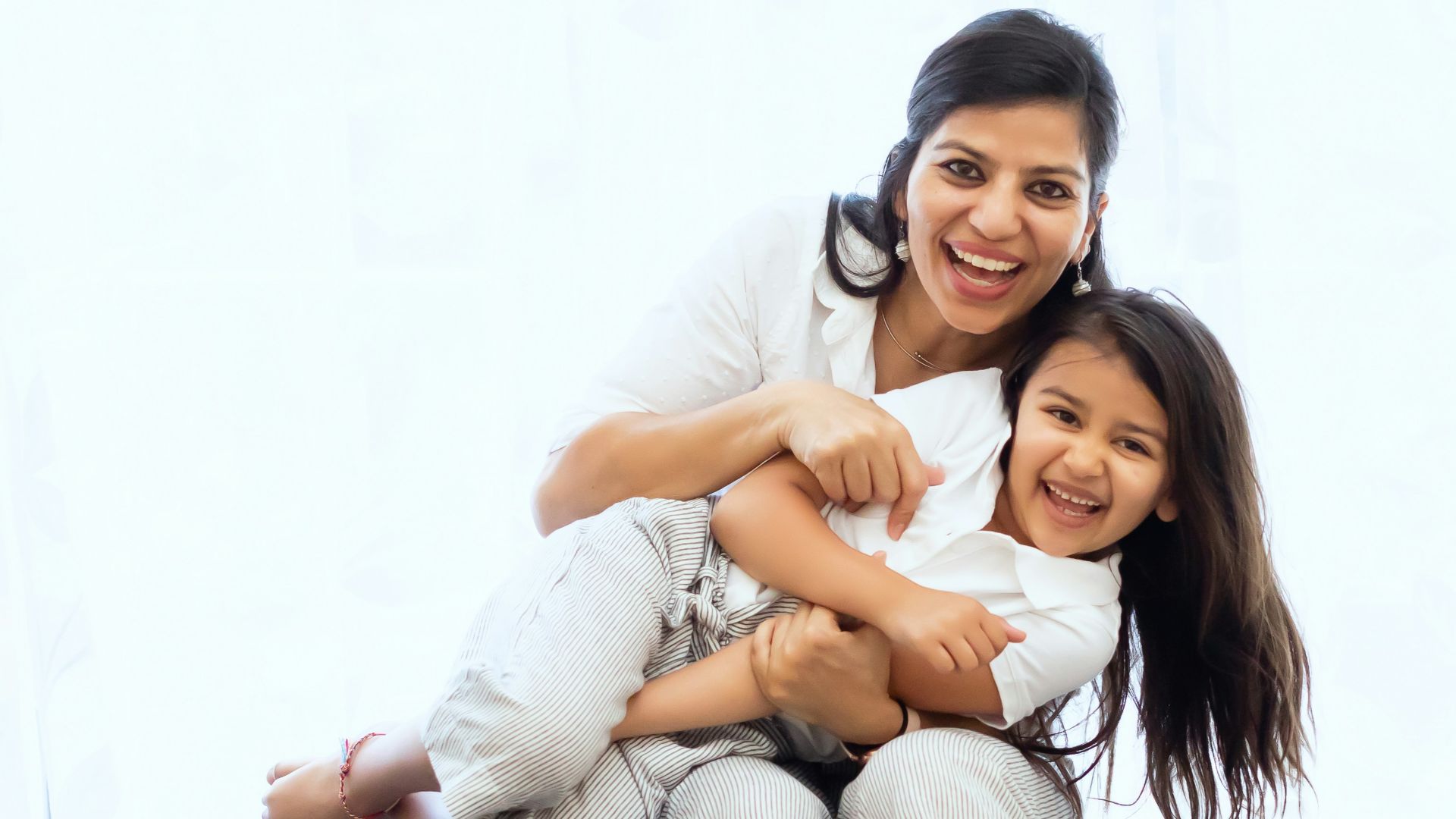 2 women sitting on gray couch