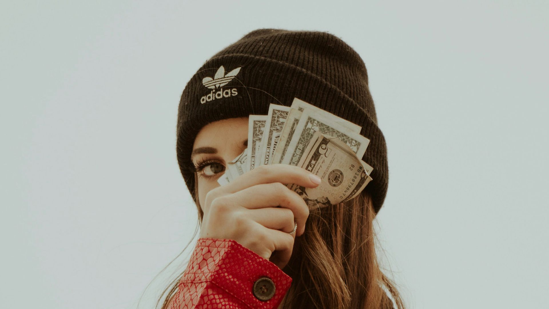 woman in black knit cap covering her face with her hand