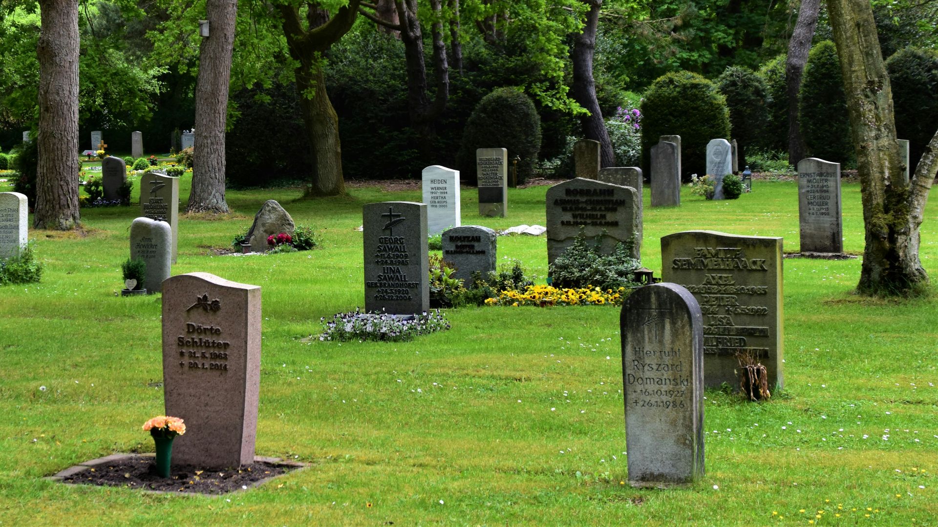 gray concrete cross on green grass field during daytime