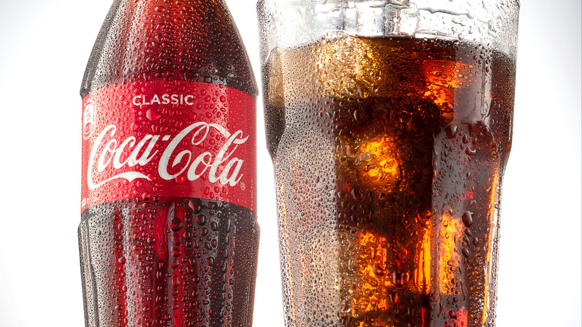 coca cola bottle beside drinking glass