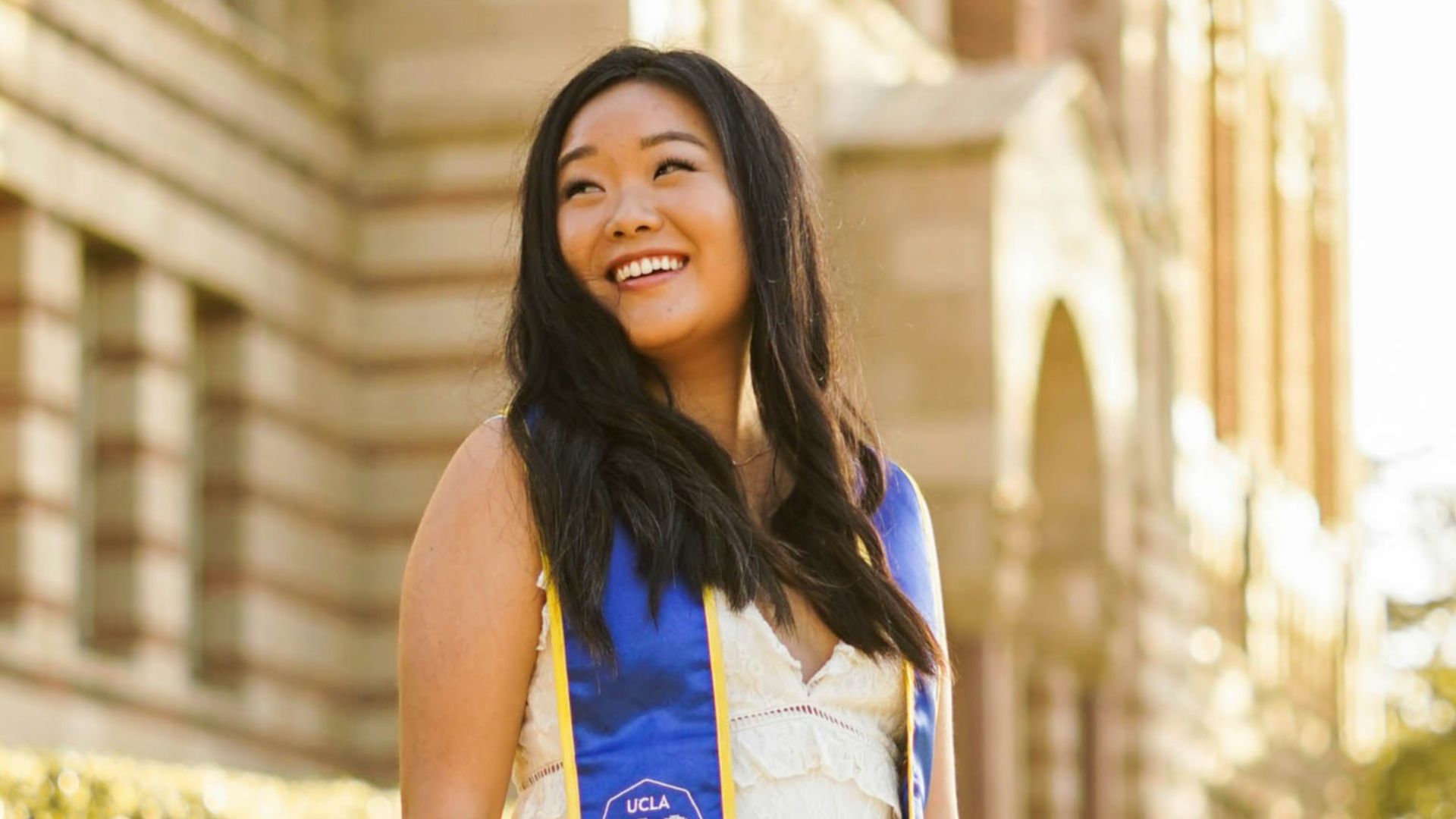 woman in blue and white sleeveless dress standing on sidewalk during daytime