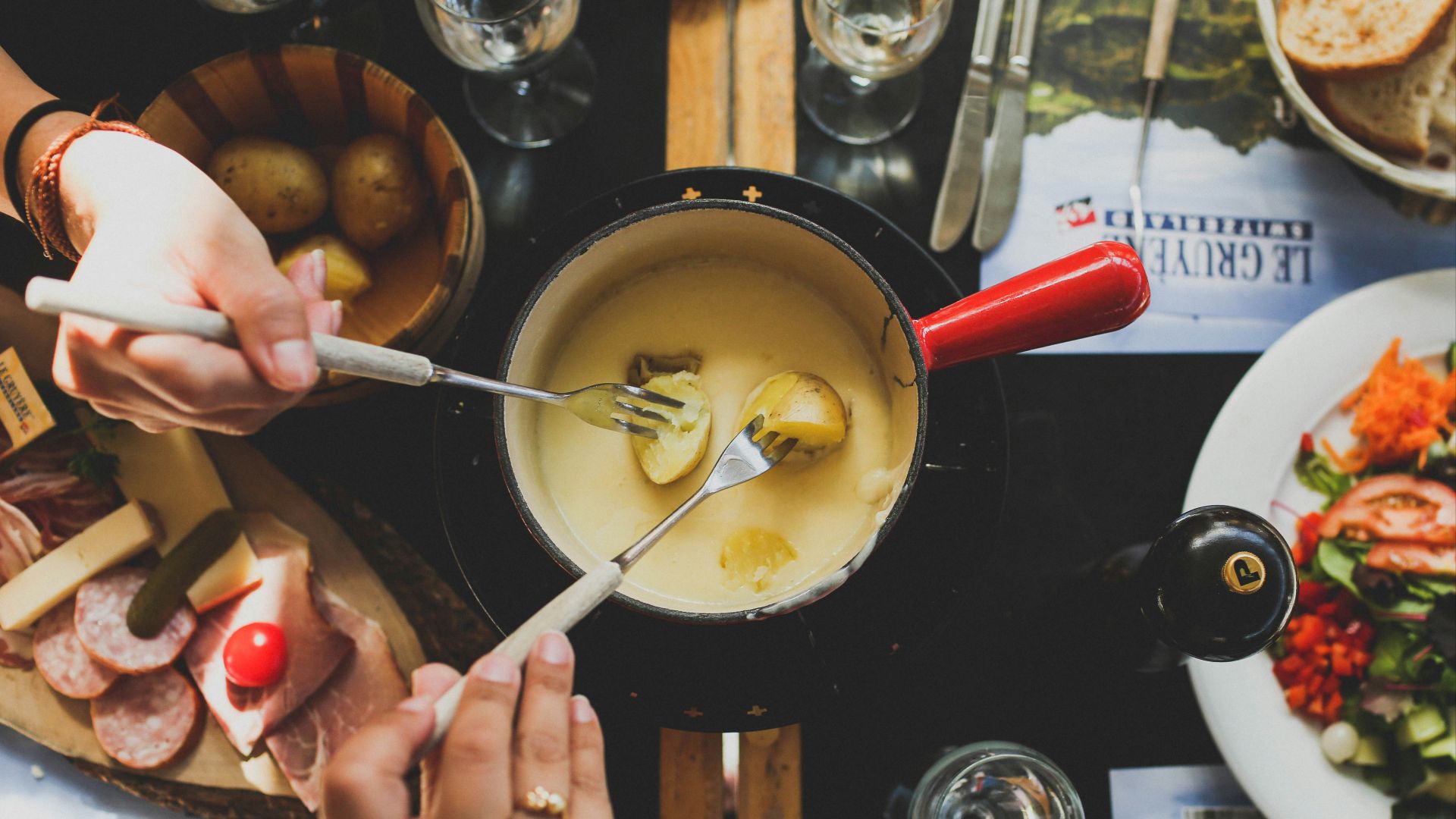 two person holding fork dipping food on sauce