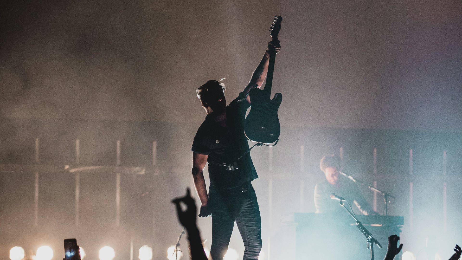 man in black shirt and black pants singing on stage