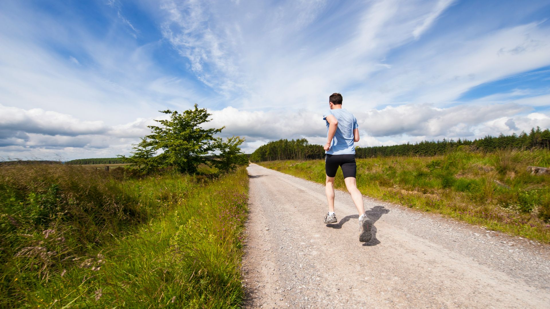 man running on road near grass field
