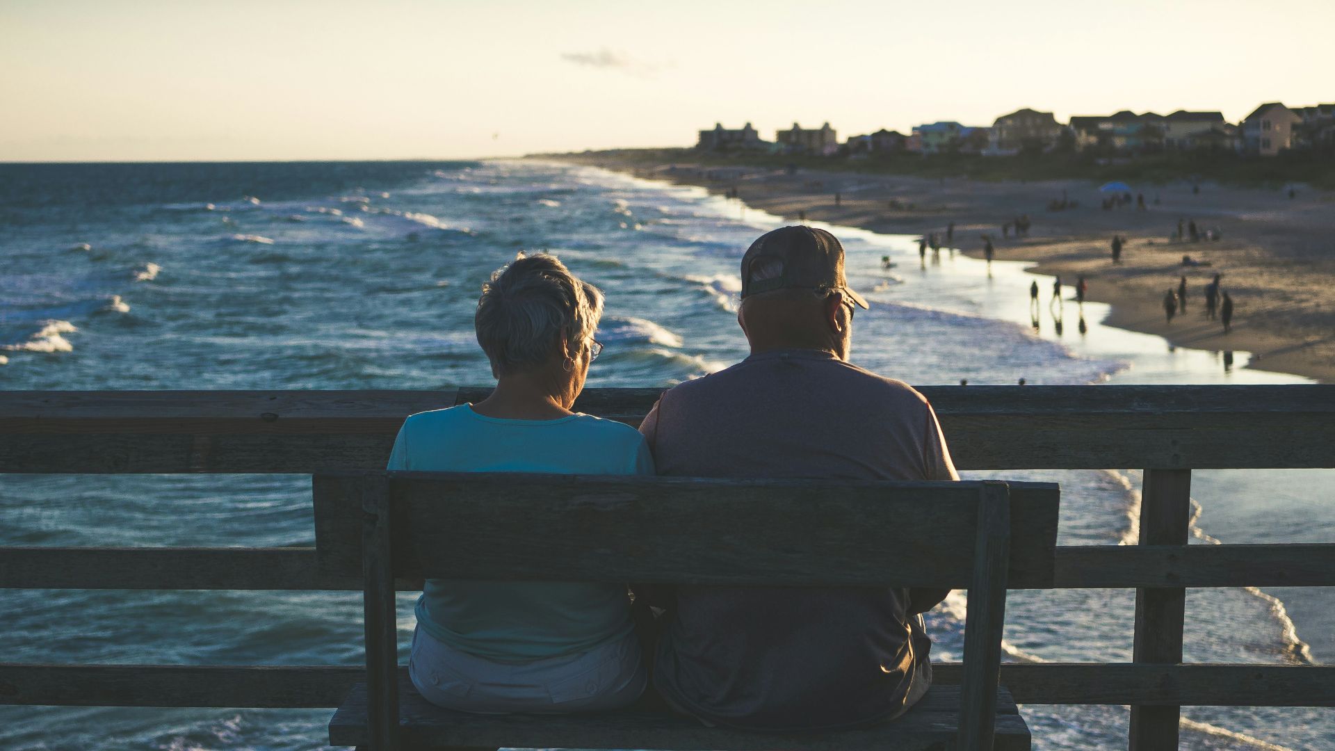 man and woman sitting on bench in front of beach