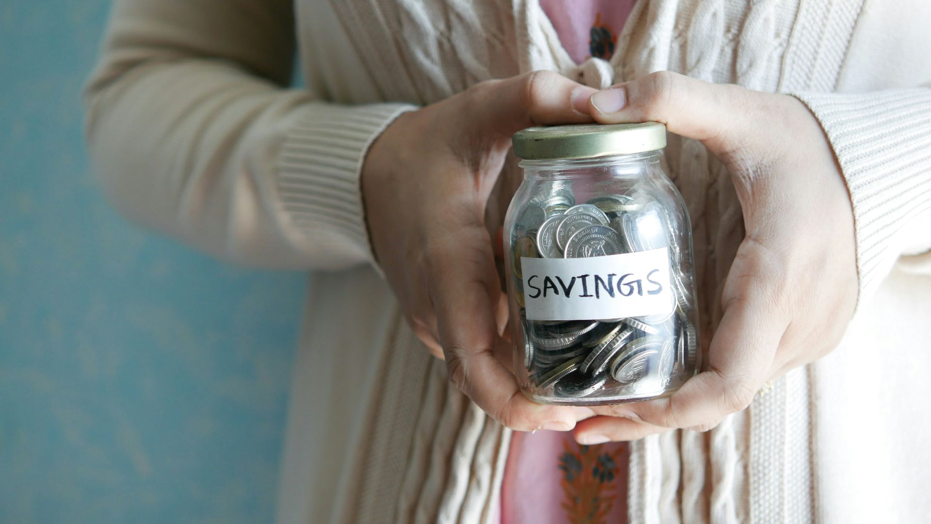 a woman holding a jar with savings written on it