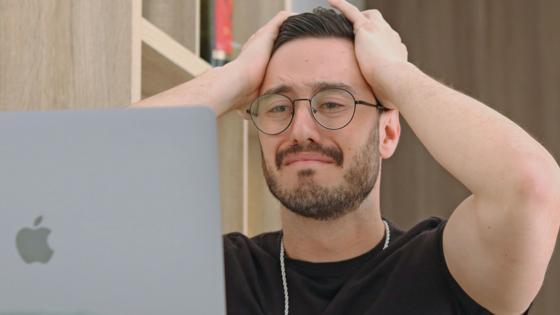 a man with glasses is looking at a laptop