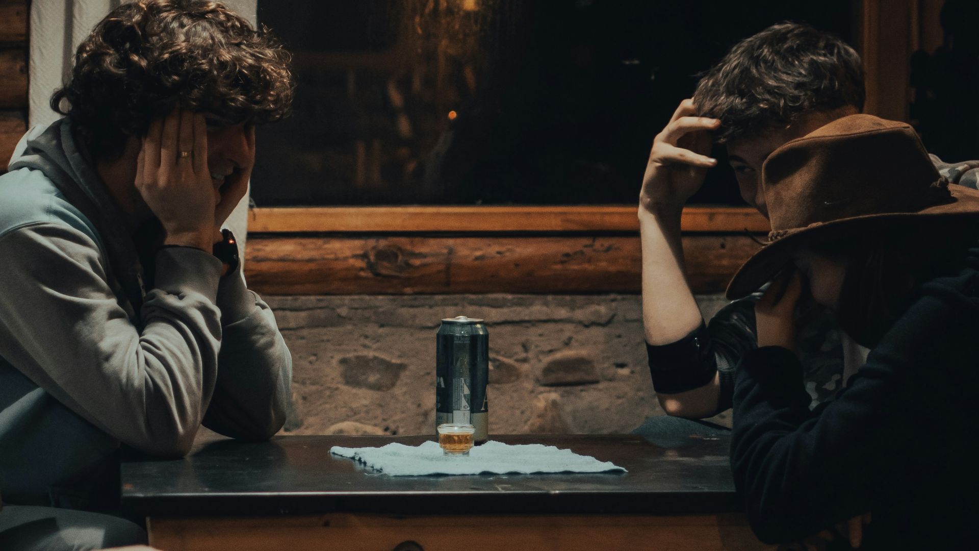 man in white hoodie sitting on brown wooden chair
