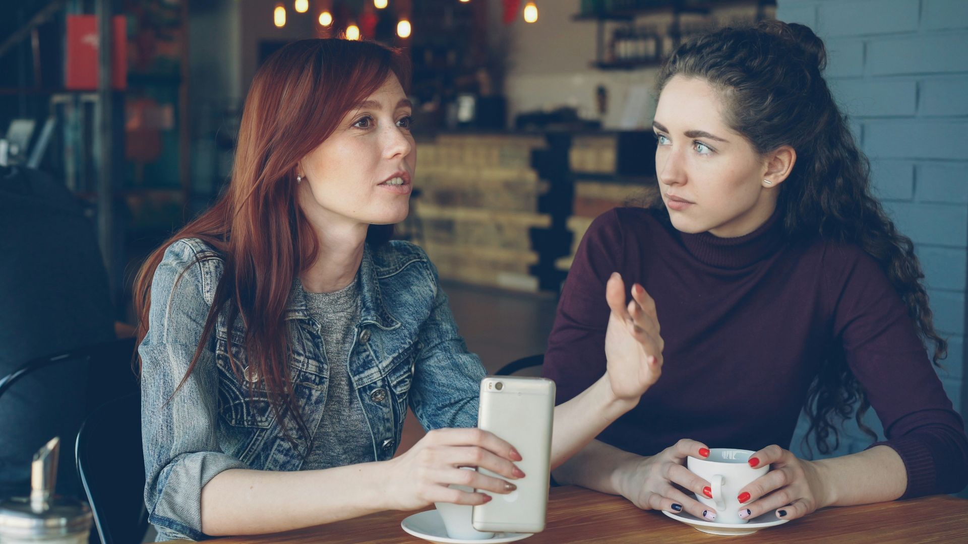 Two women converse at a cafe.