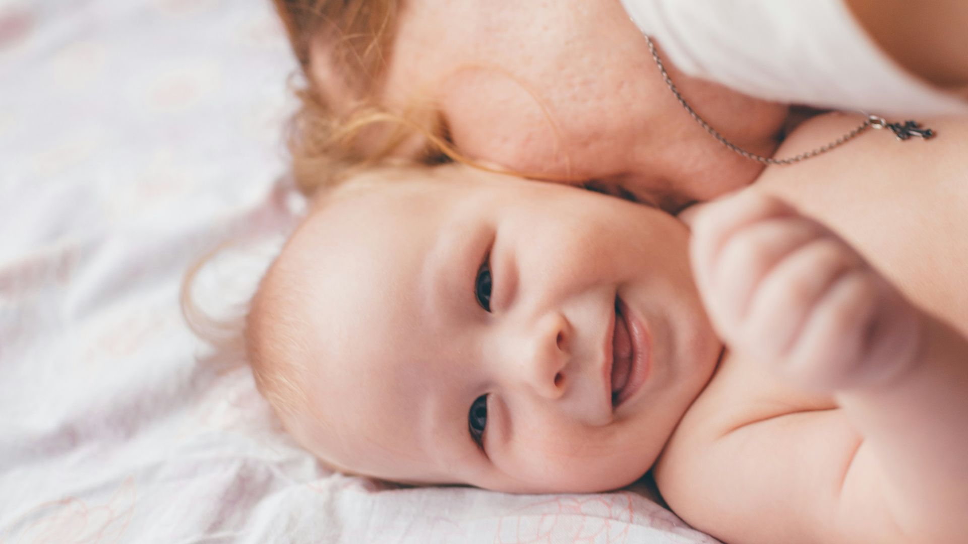 baby in white shirt lying on bed