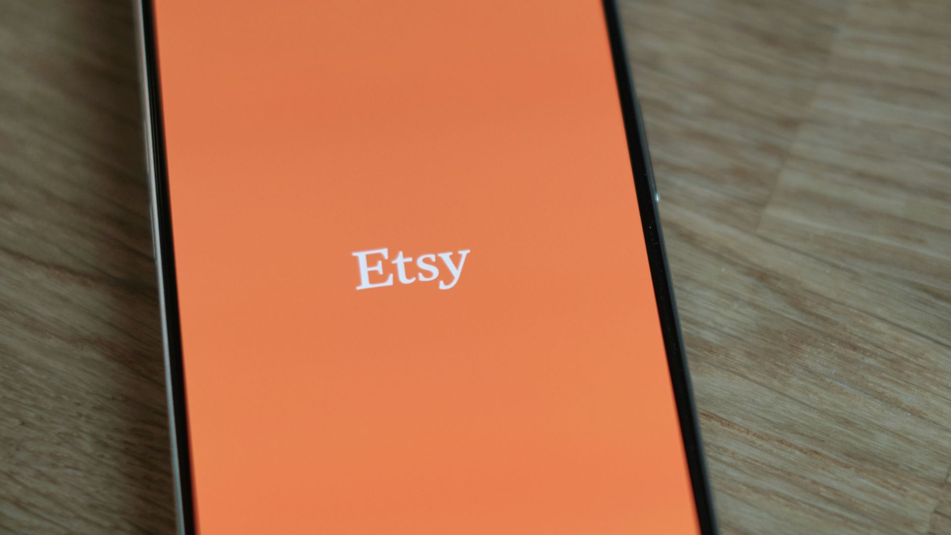 An orange cell phone sitting on top of a wooden table
