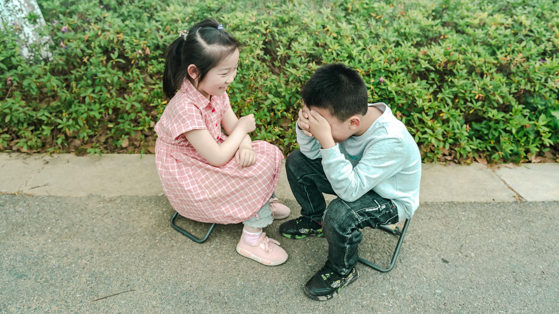 a boy and a girl sitting on a bench