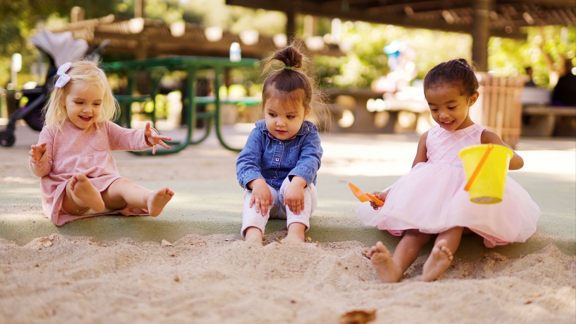 girl in pink dress sitting on brown sand during daytime