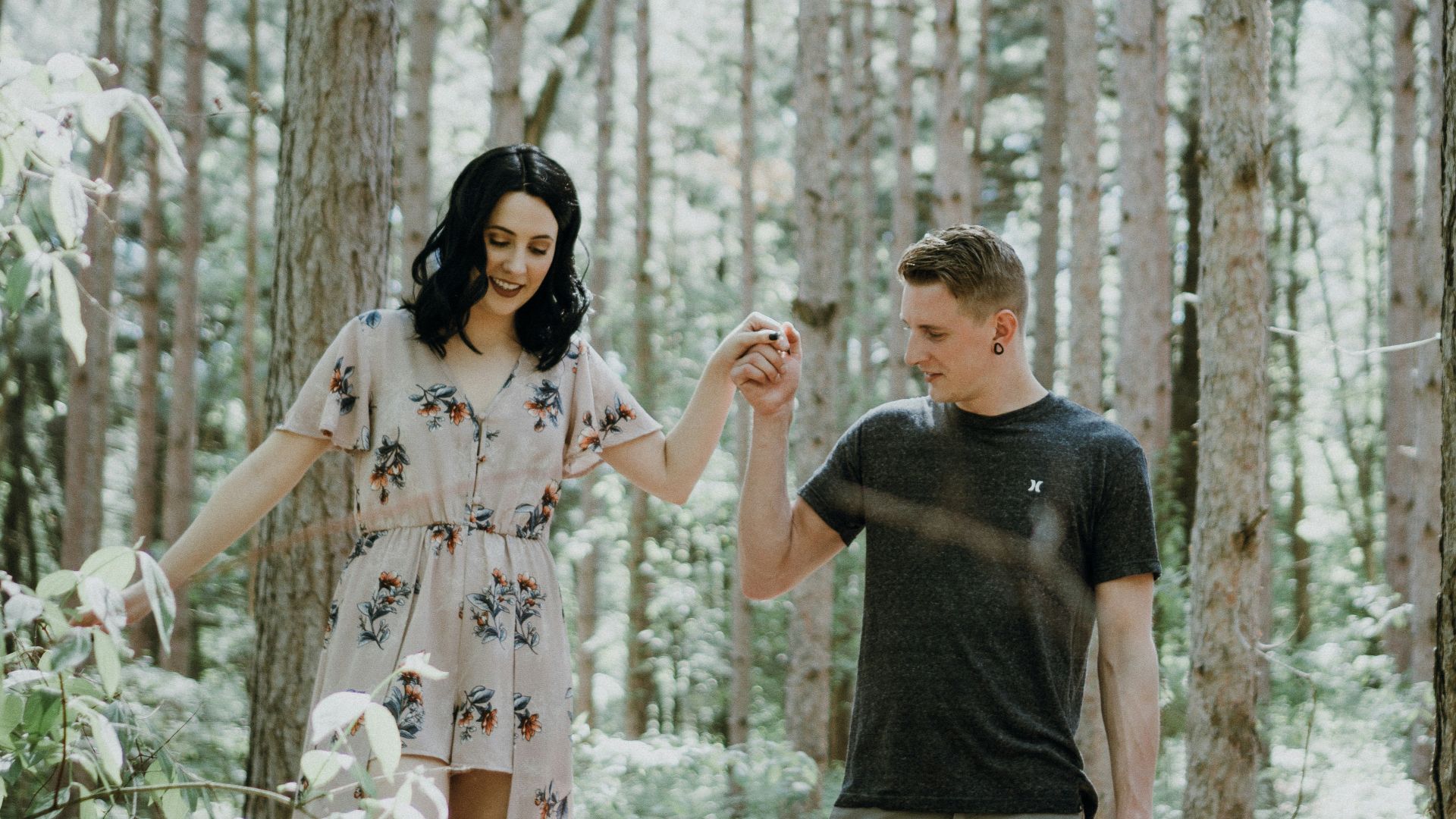 man holding hands with woman near trees