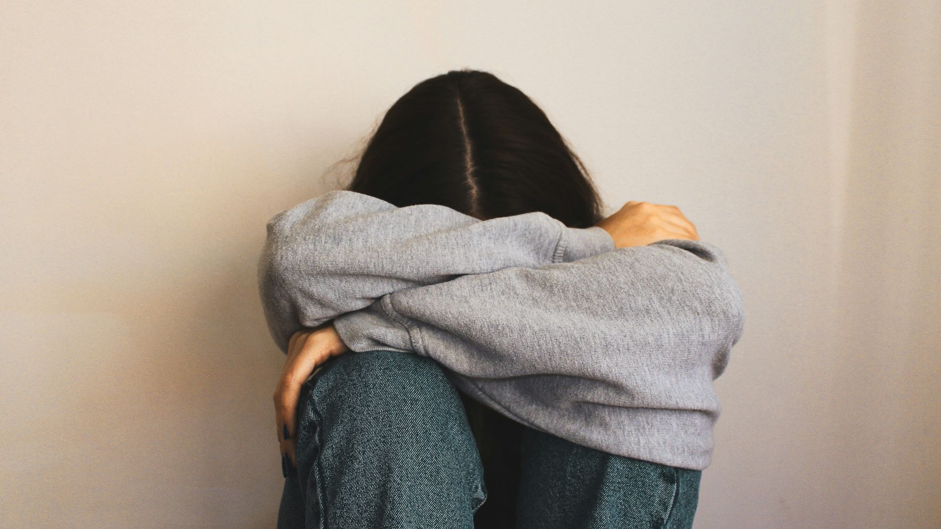 a woman sitting on the floor with her arms wrapped around her head