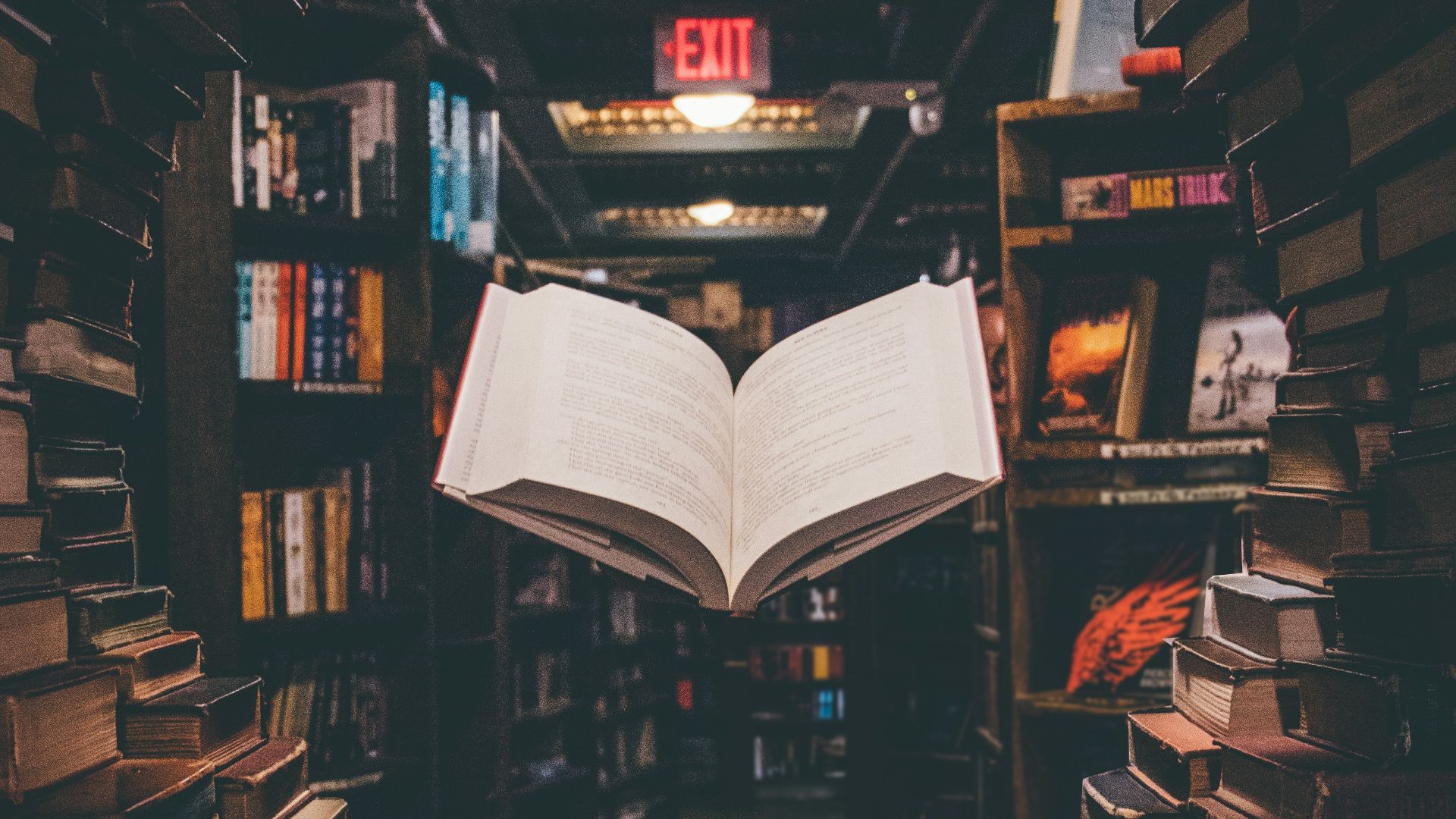 view of floating open book from stacked books in library
