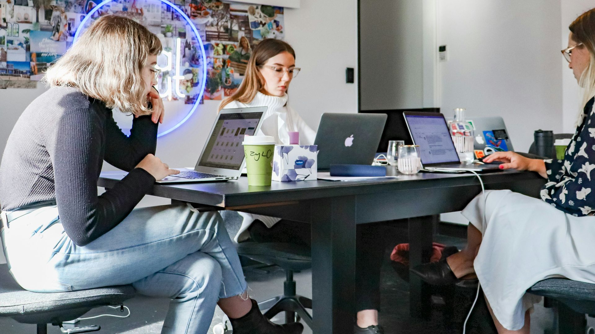3 women sitting on chair in front of table with laptop computers