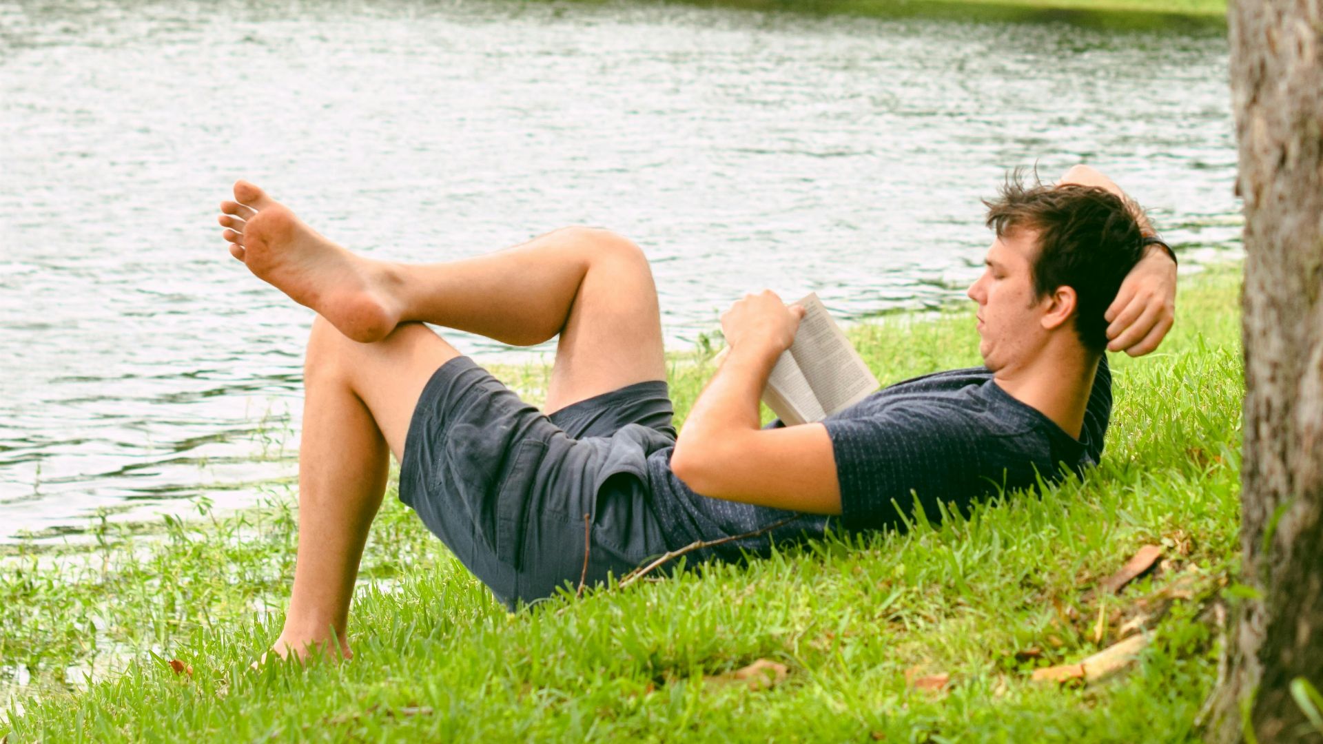 man on grass while reading book