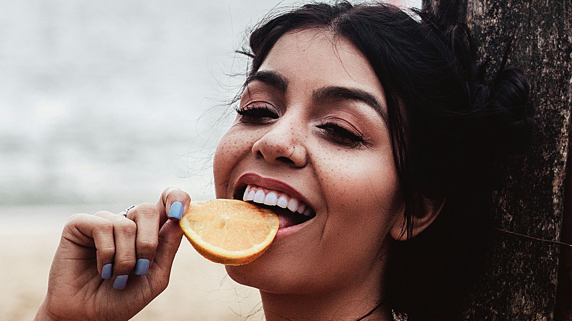 a woman sitting on the beach brushing her teeth