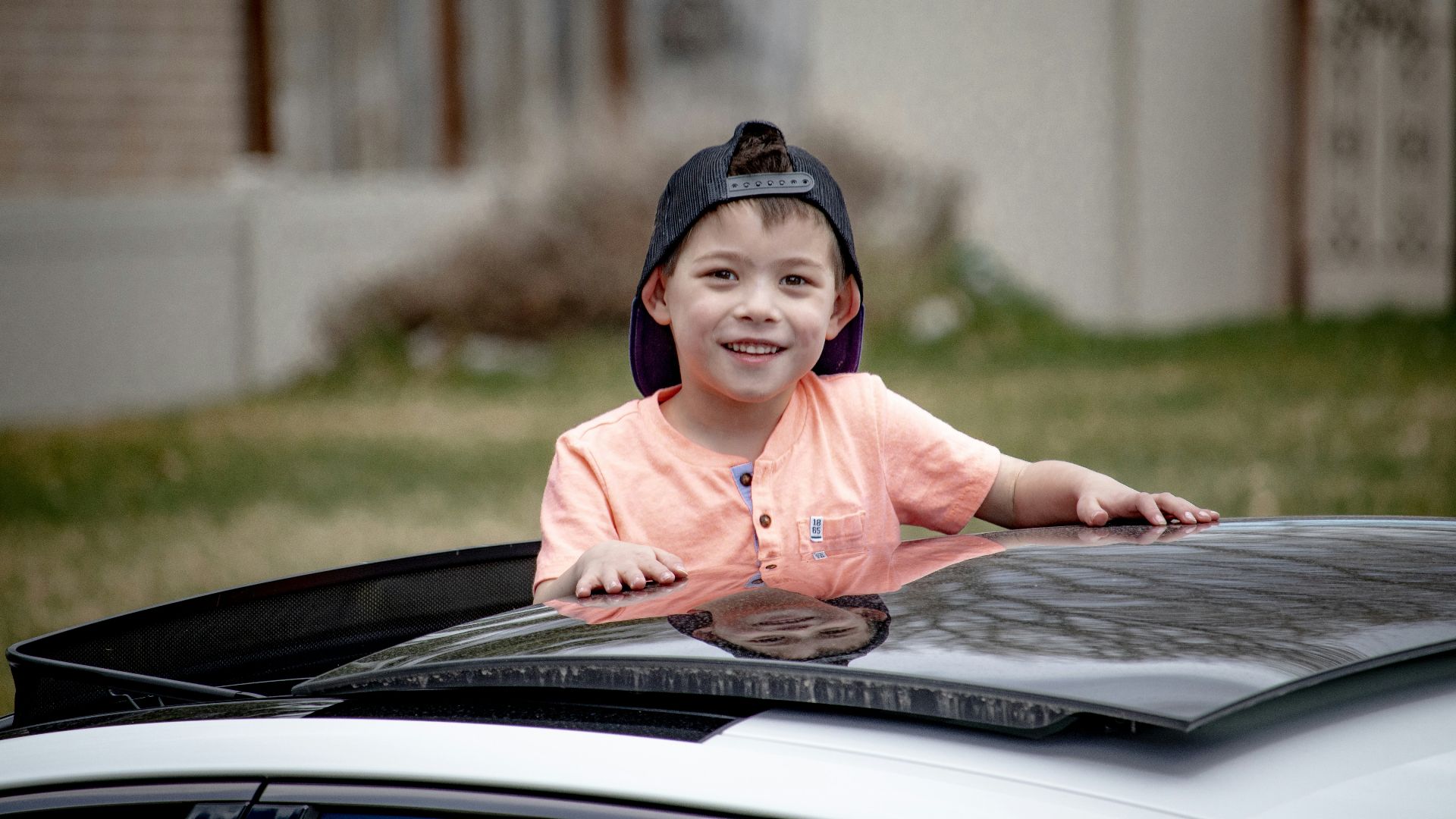 girl in pink long sleeve shirt and black knit cap sitting on black car hood during