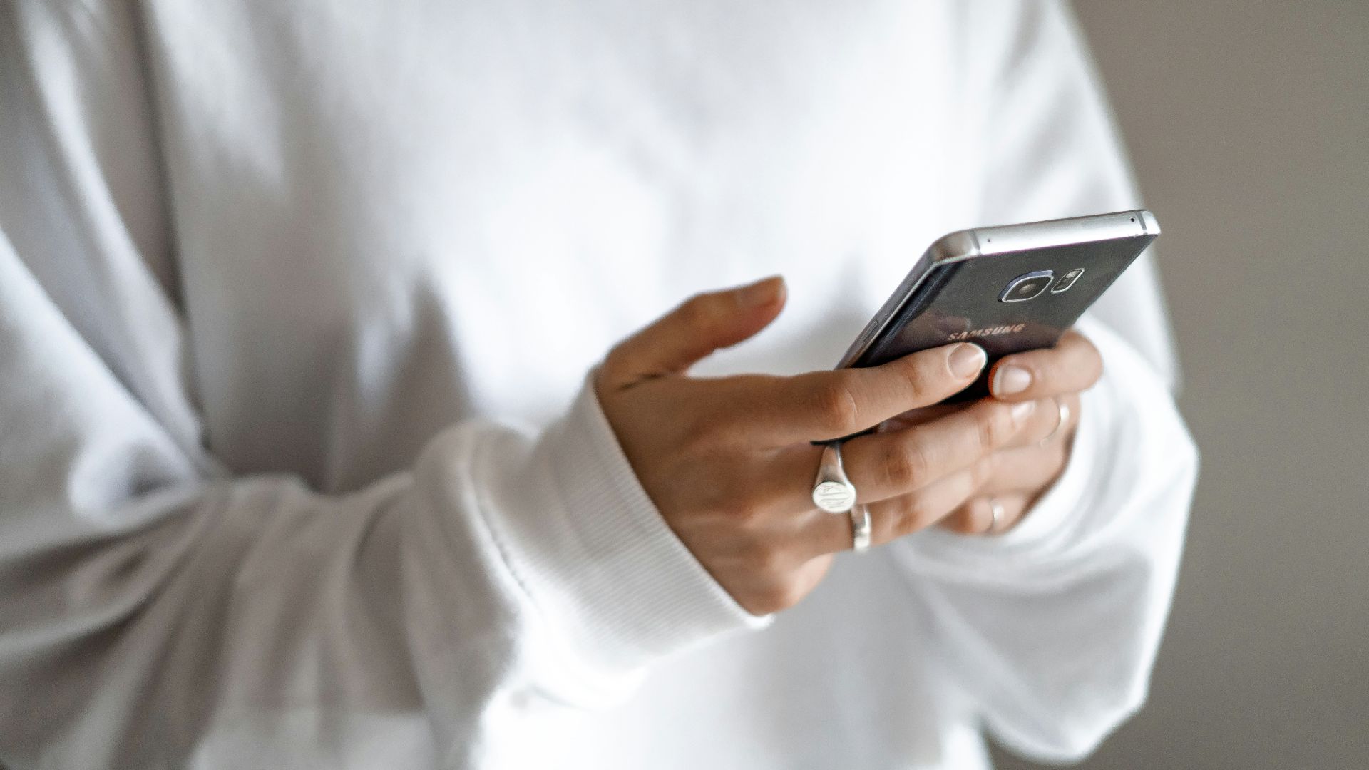 person in white long sleeve shirt holding black smartphone
