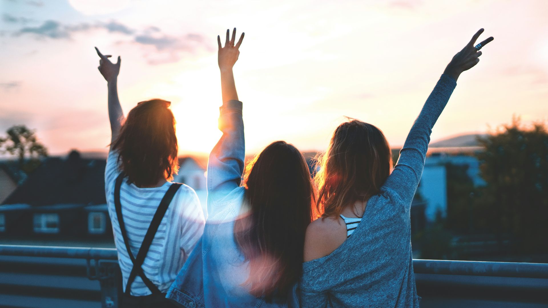 photo of three women lifting there hands \