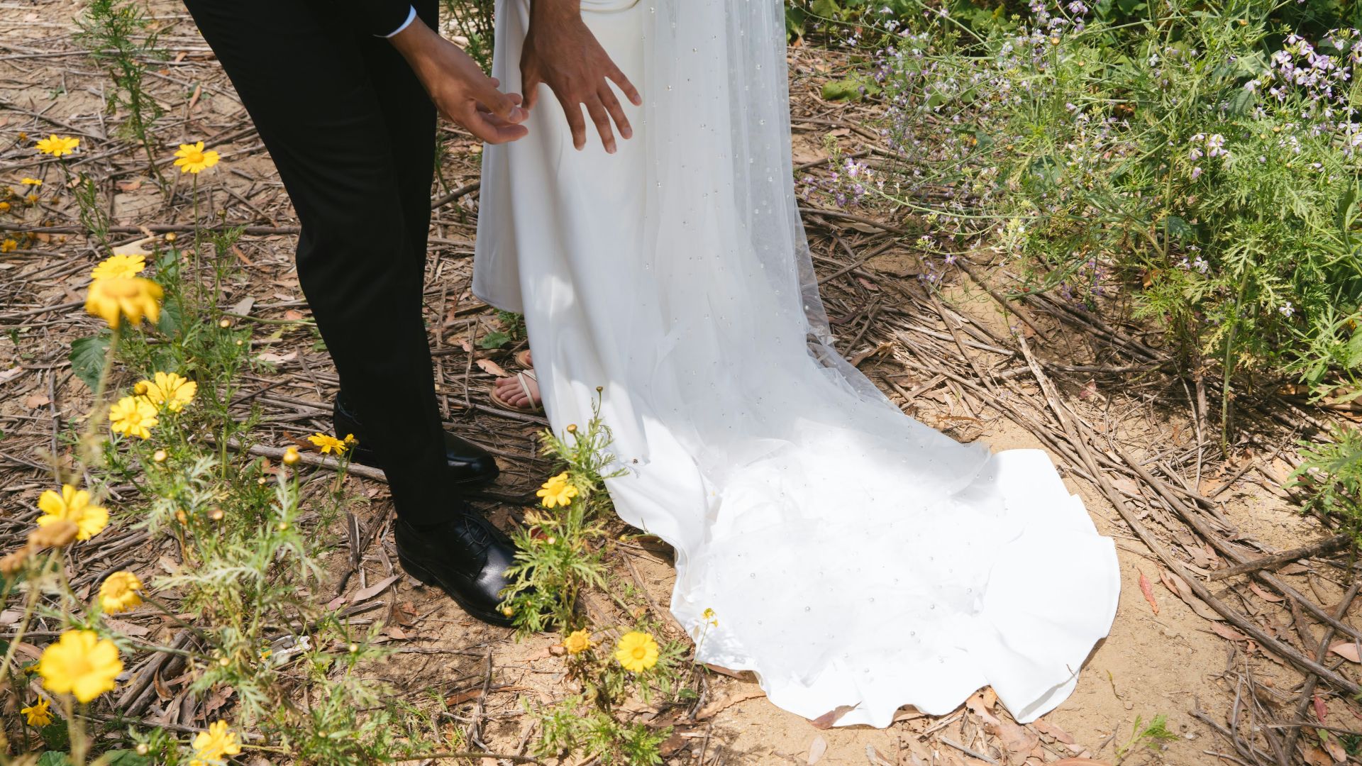 a bride and groom standing in a field of wildflowers