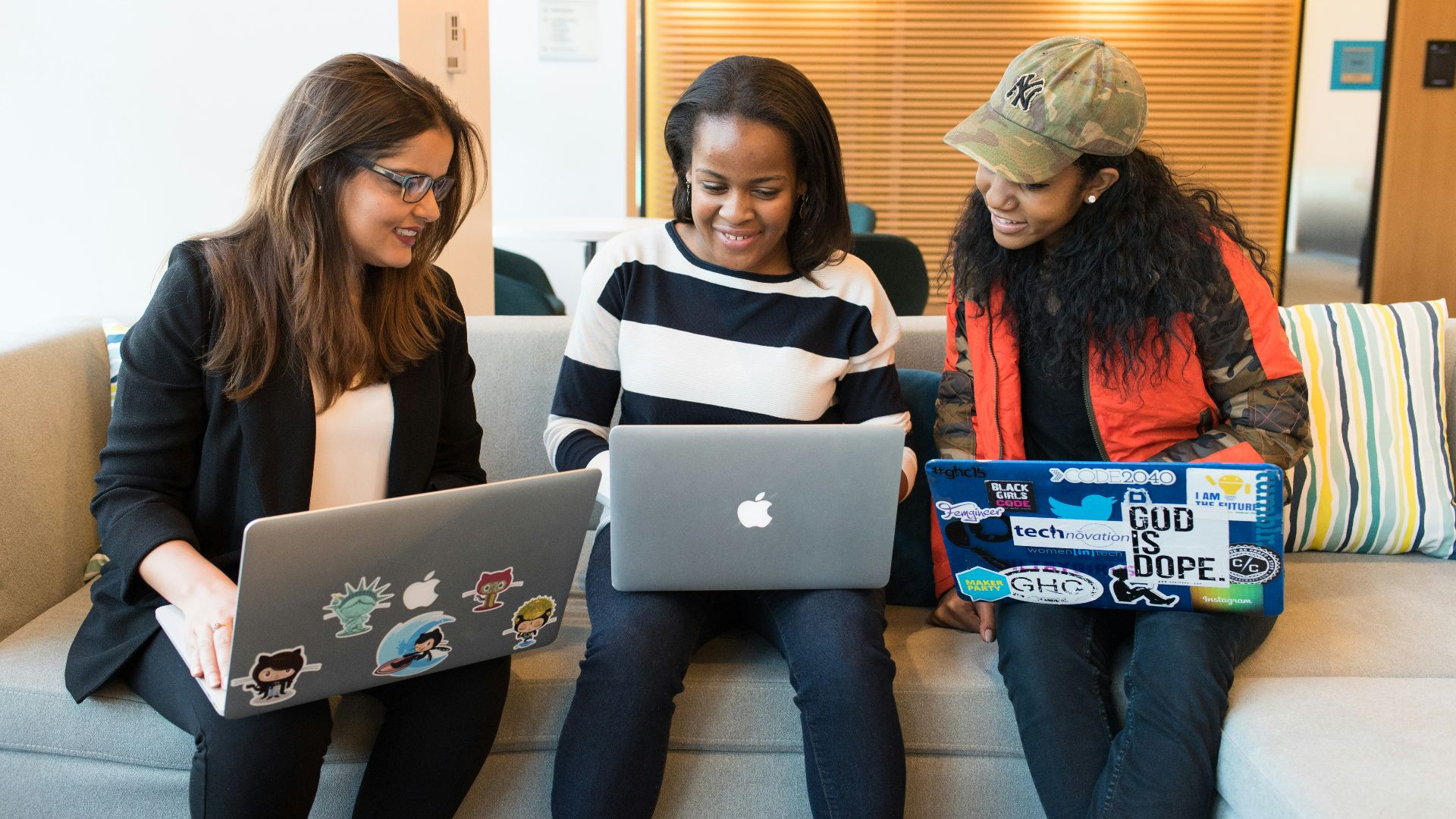 three women sitting on sofa with MacBook
