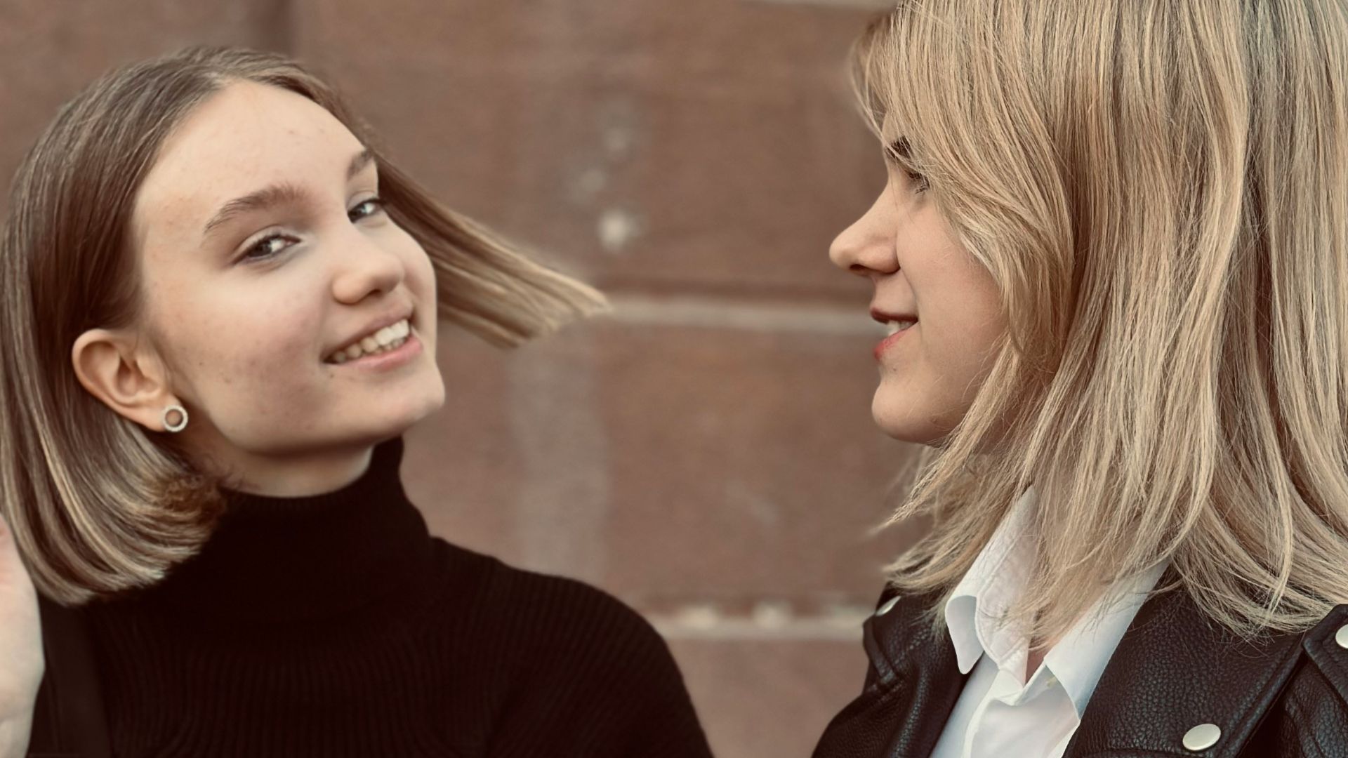 Two women standing next to each other in front of a building