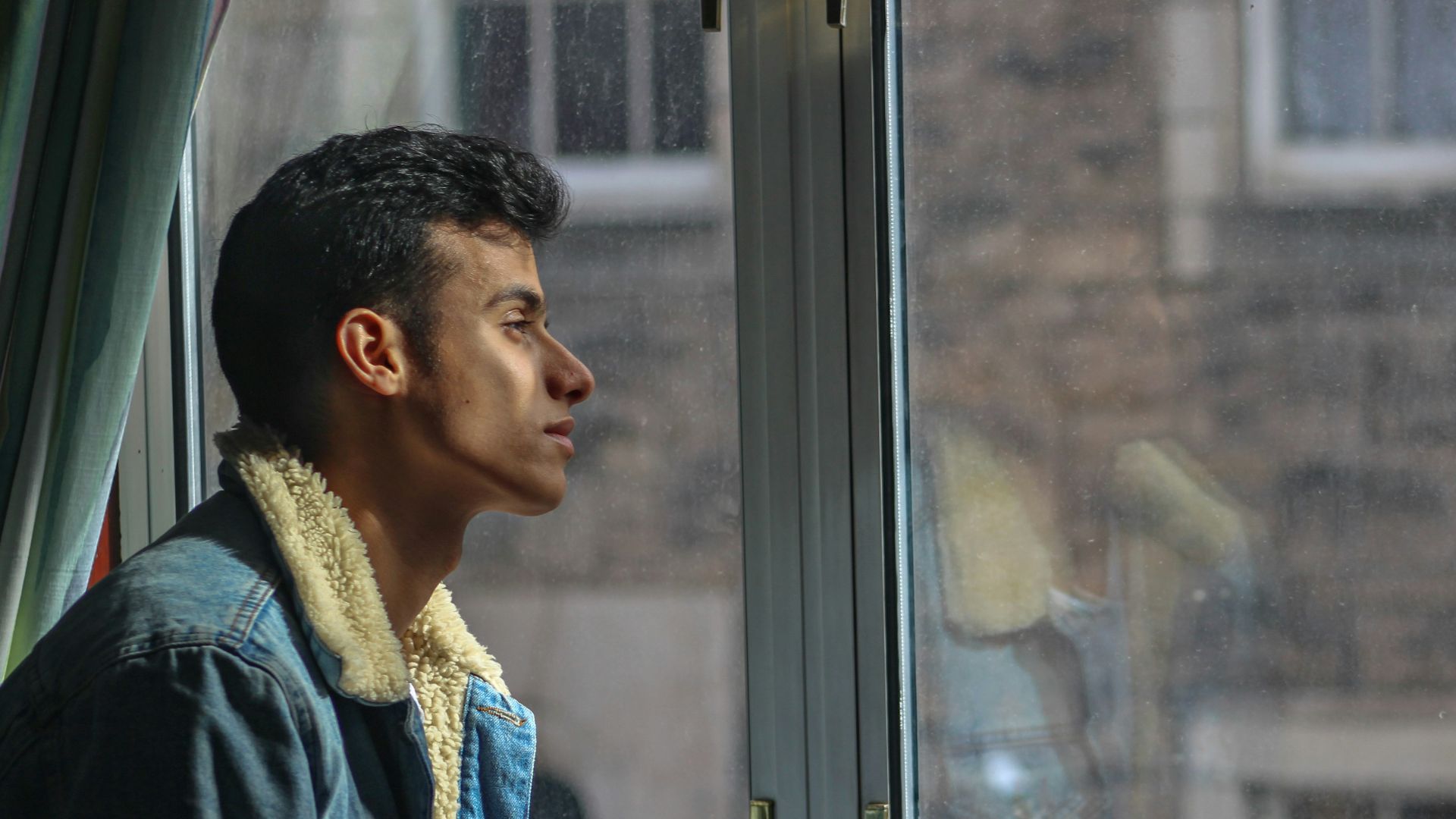 man in black jacket looking out the window