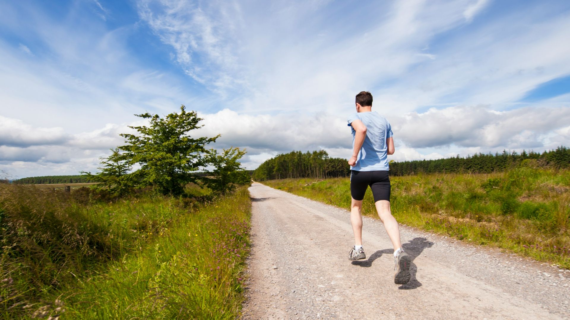 man running on road near grass field