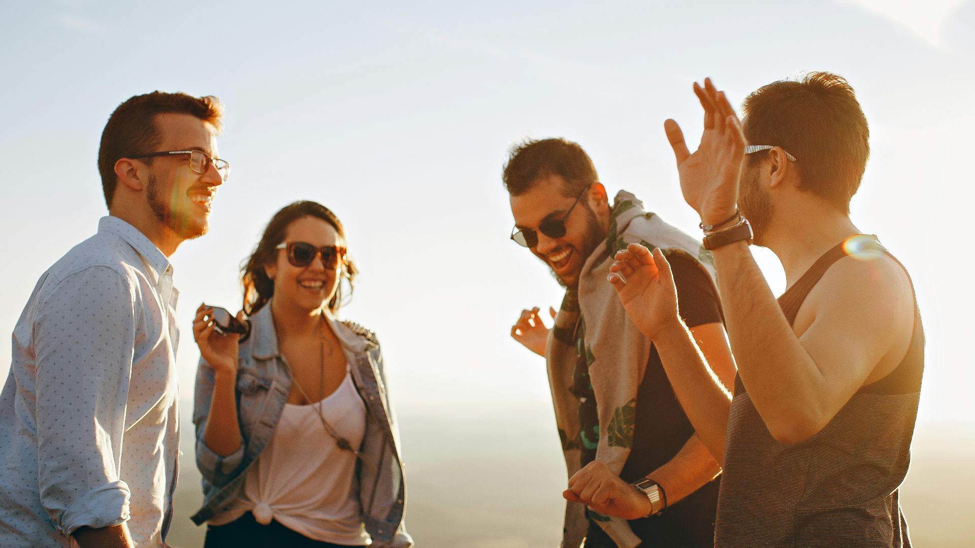 three men and one woman laughing during daytime