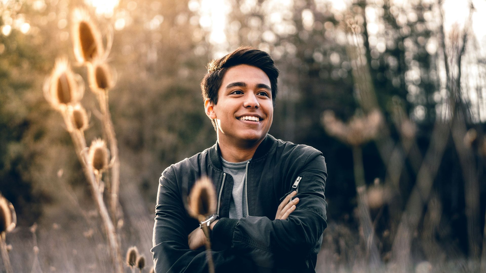 smiling man standing near green trees