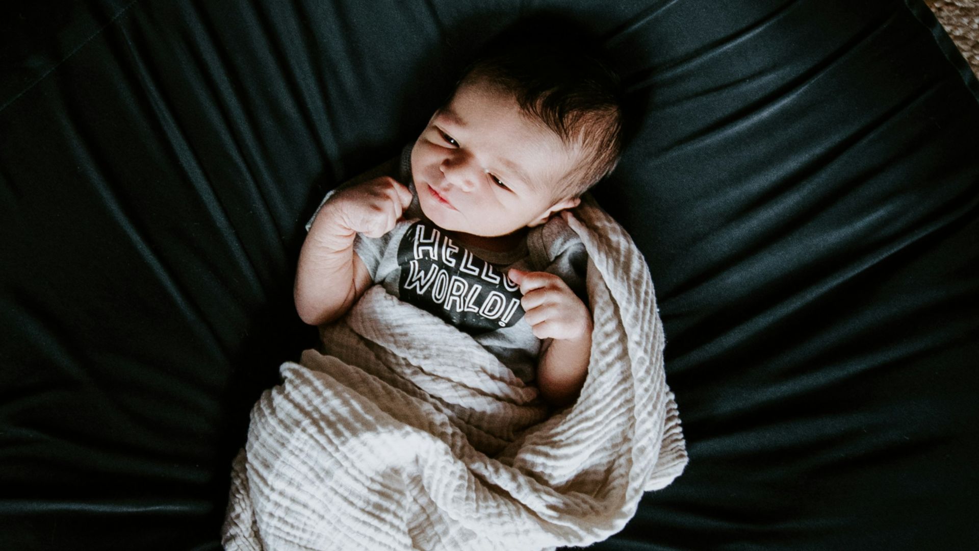 girl in white sweater and black pants lying on black round bed