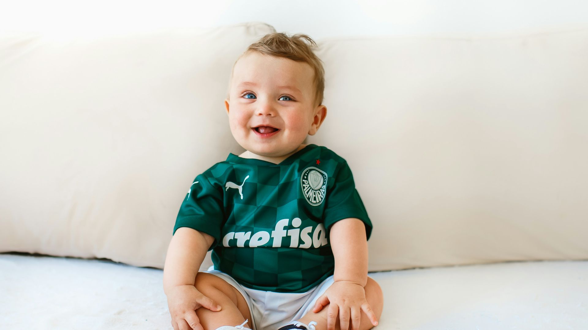 boy in green and white crew neck t-shirt sitting on white bed