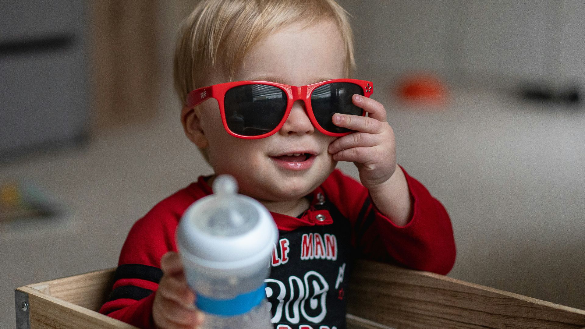 boy in red sweater holding white plastic bottle