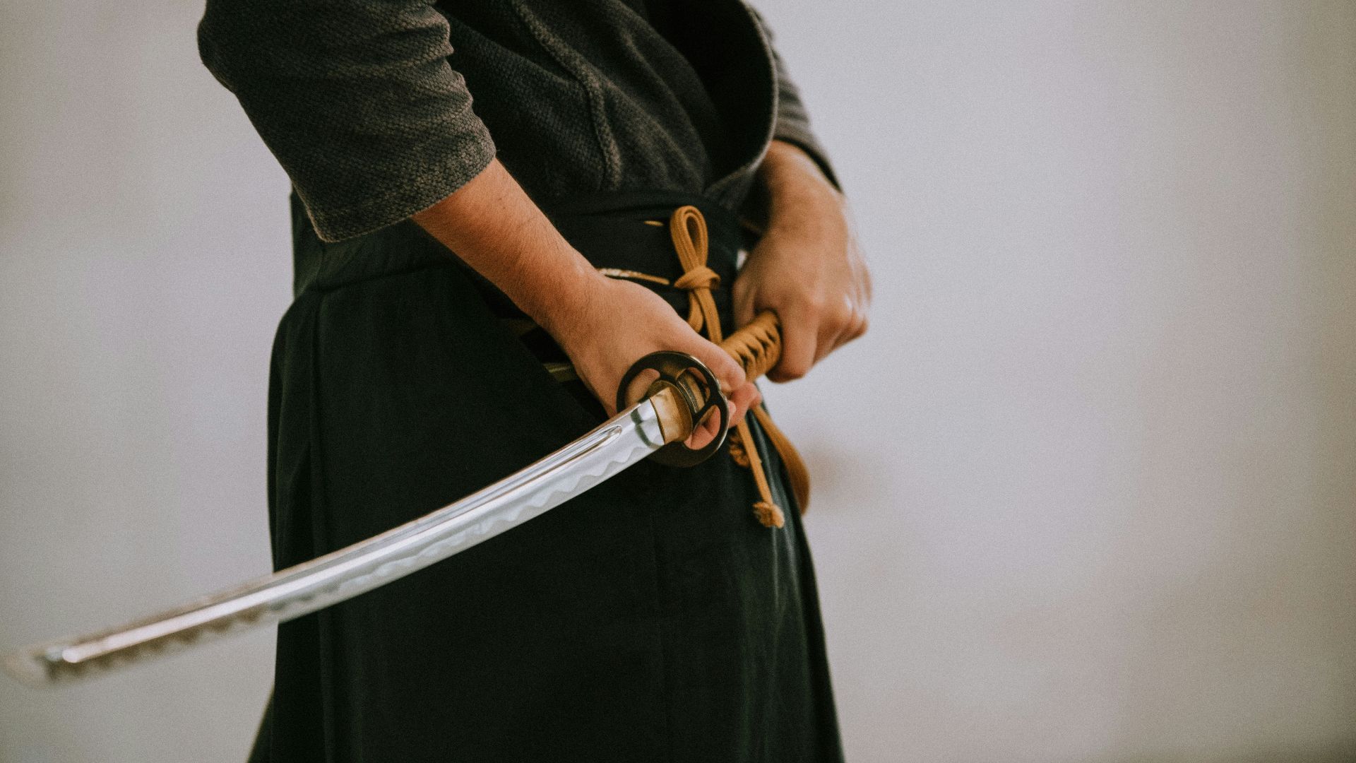 person in black long sleeve shirt and black skirt holding white leather belt