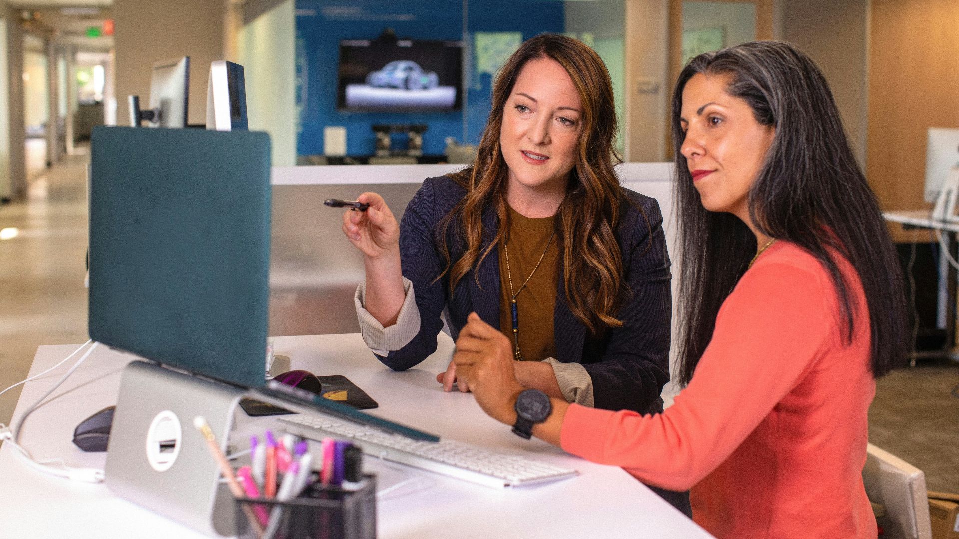 two women sitting at a table looking at a computer screen
