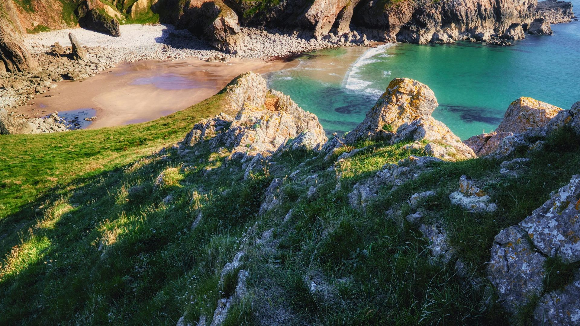 rocky hill with grass facing ocean