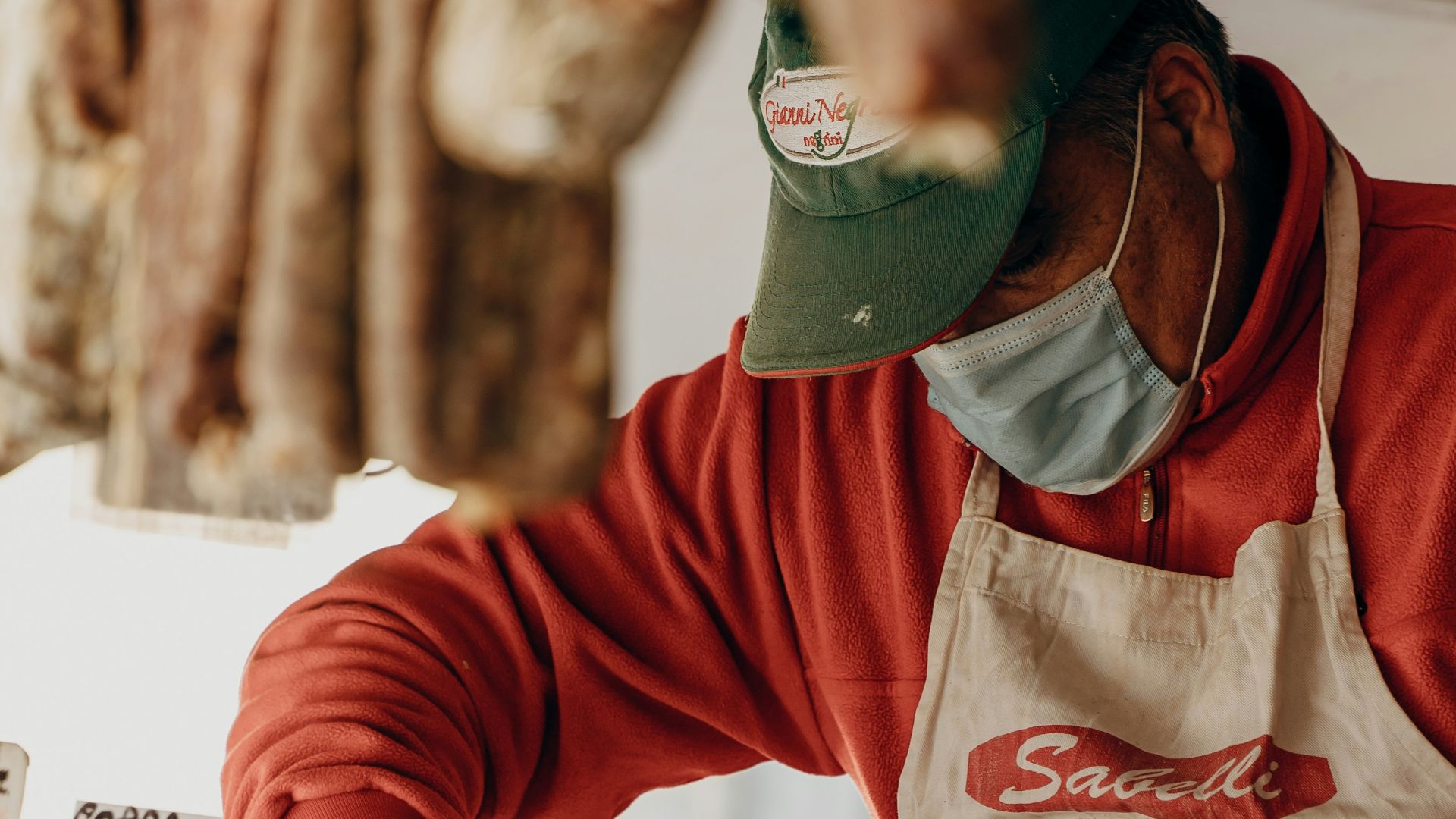 person in red and white long sleeve shirt slicing meat