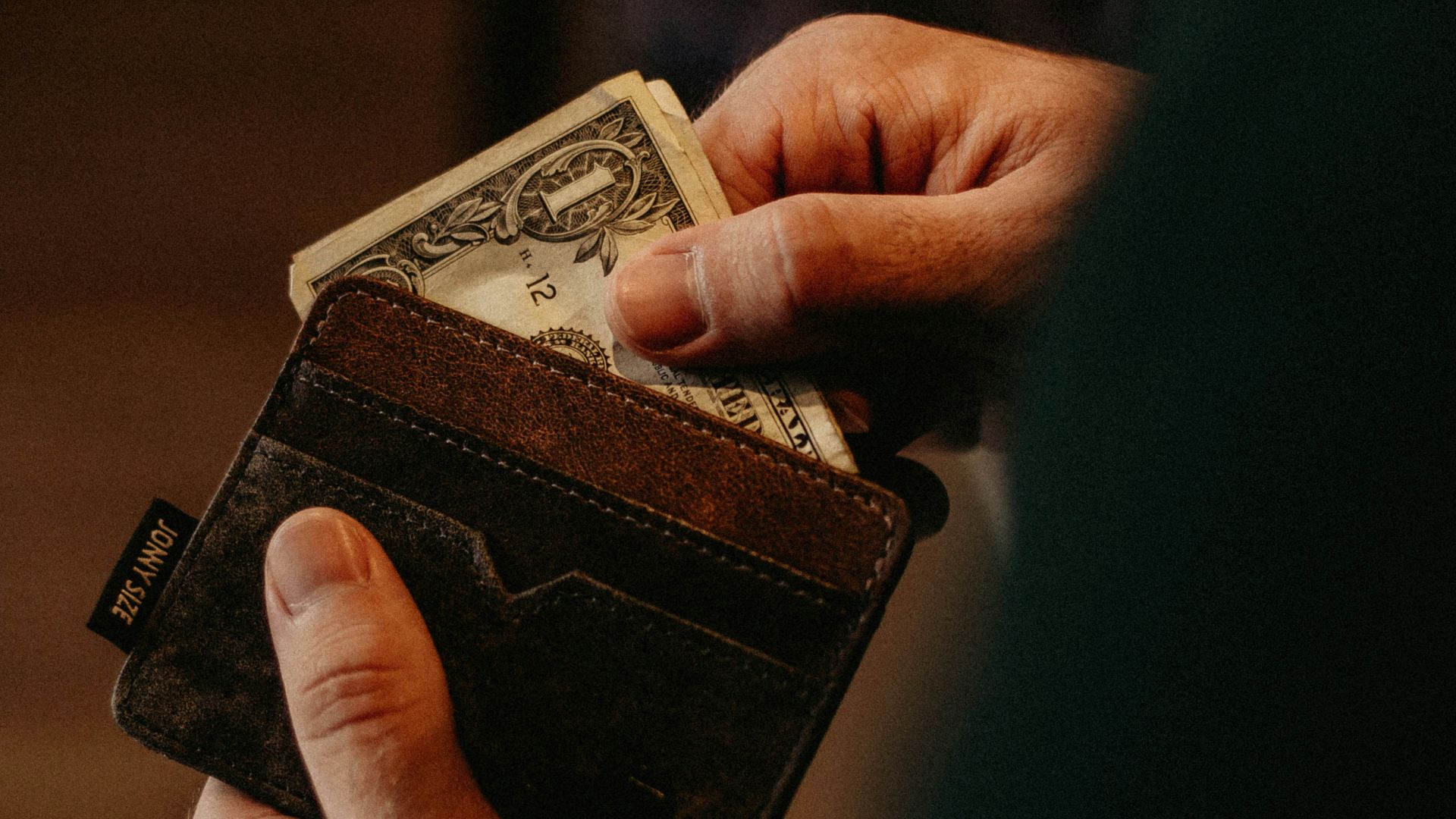 person getting 1 U.S. dollar banknote in wallet