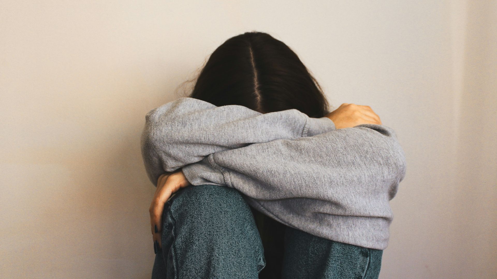 a woman sitting on the floor with her arms wrapped around her head