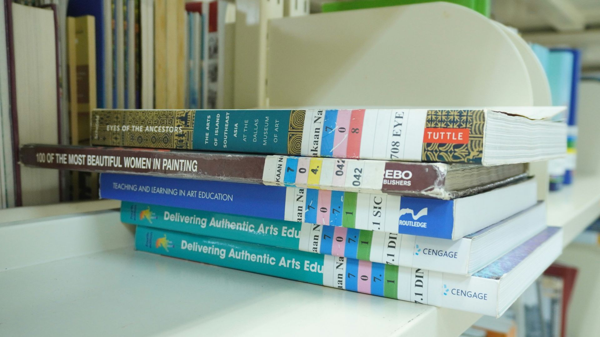 A stack of books sitting on top of a white shelf