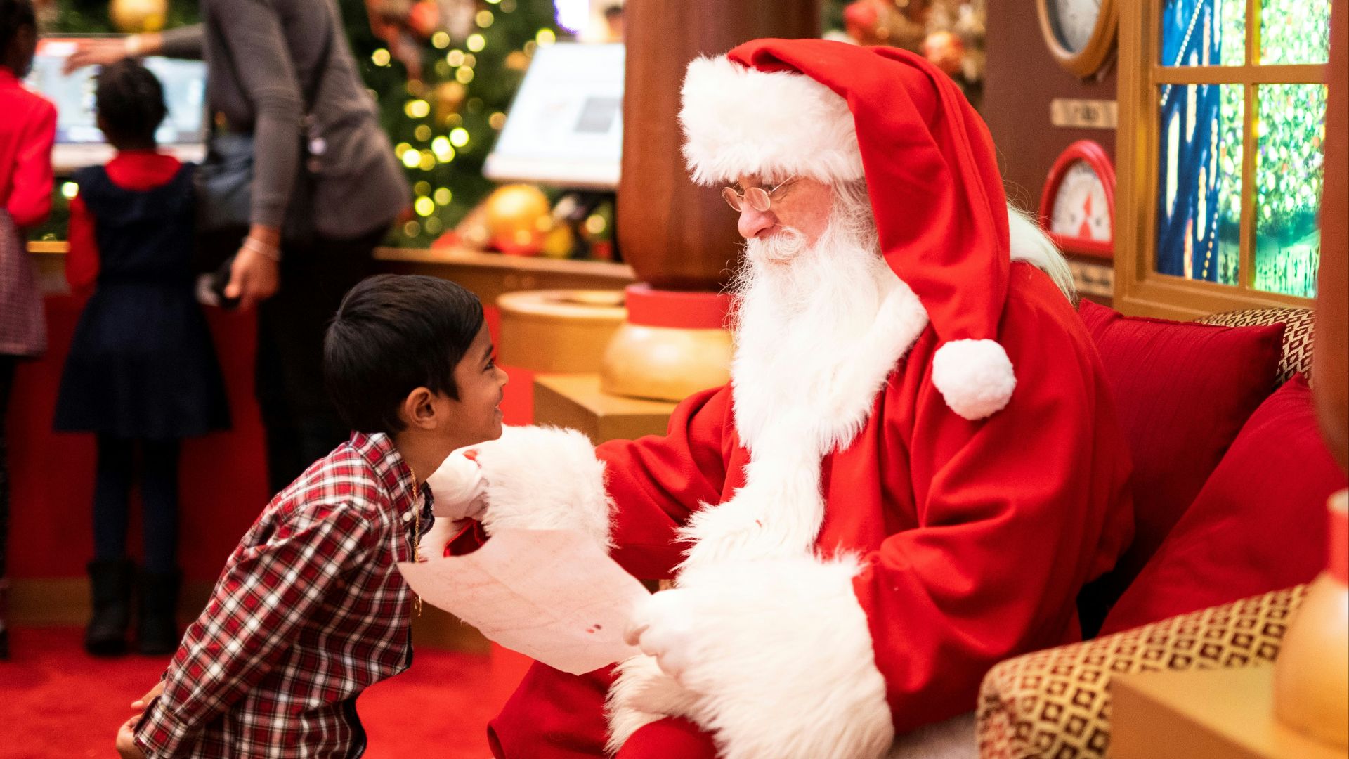 boy standing in front of man wearing Santa Claus costume