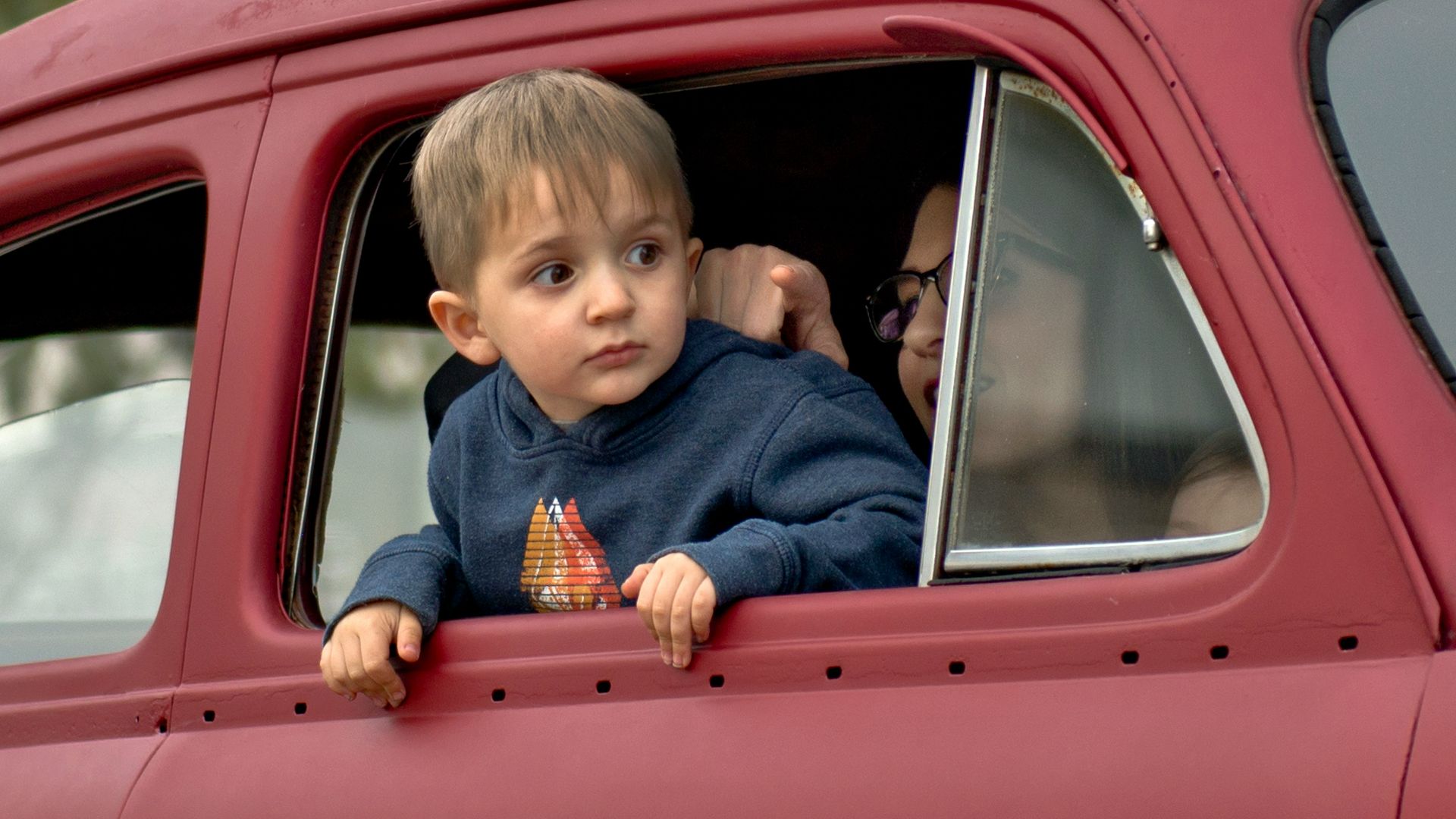 toddler riding on red vehicle