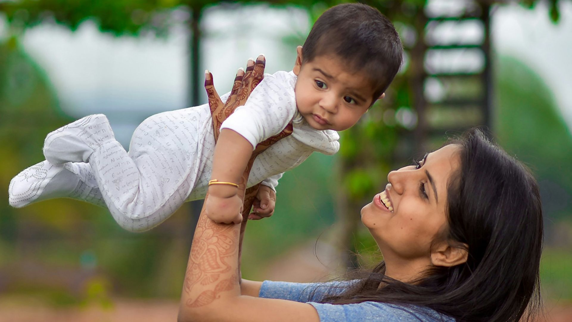 woman in blue denim button up shirt carrying girl in white long sleeve shirt during daytime