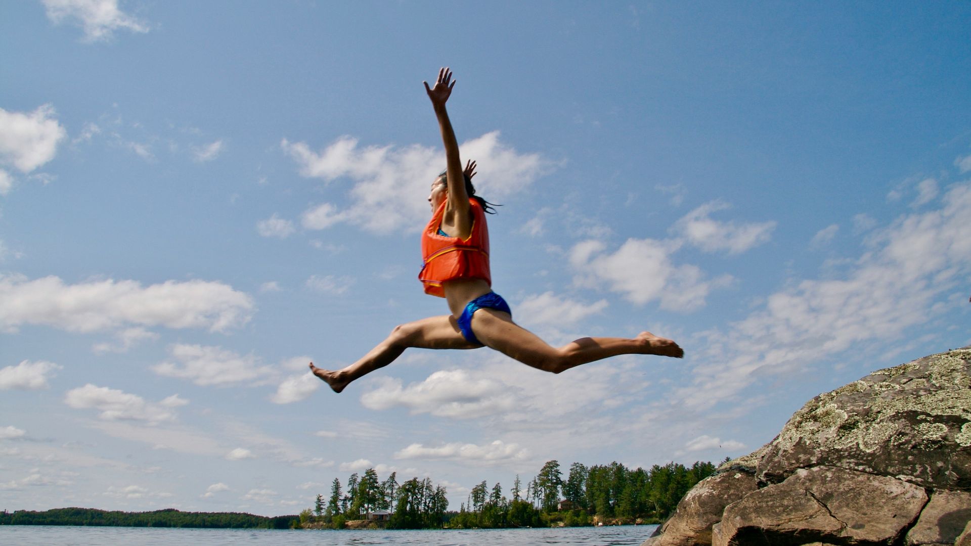 woman jumping towards water wearing life vest